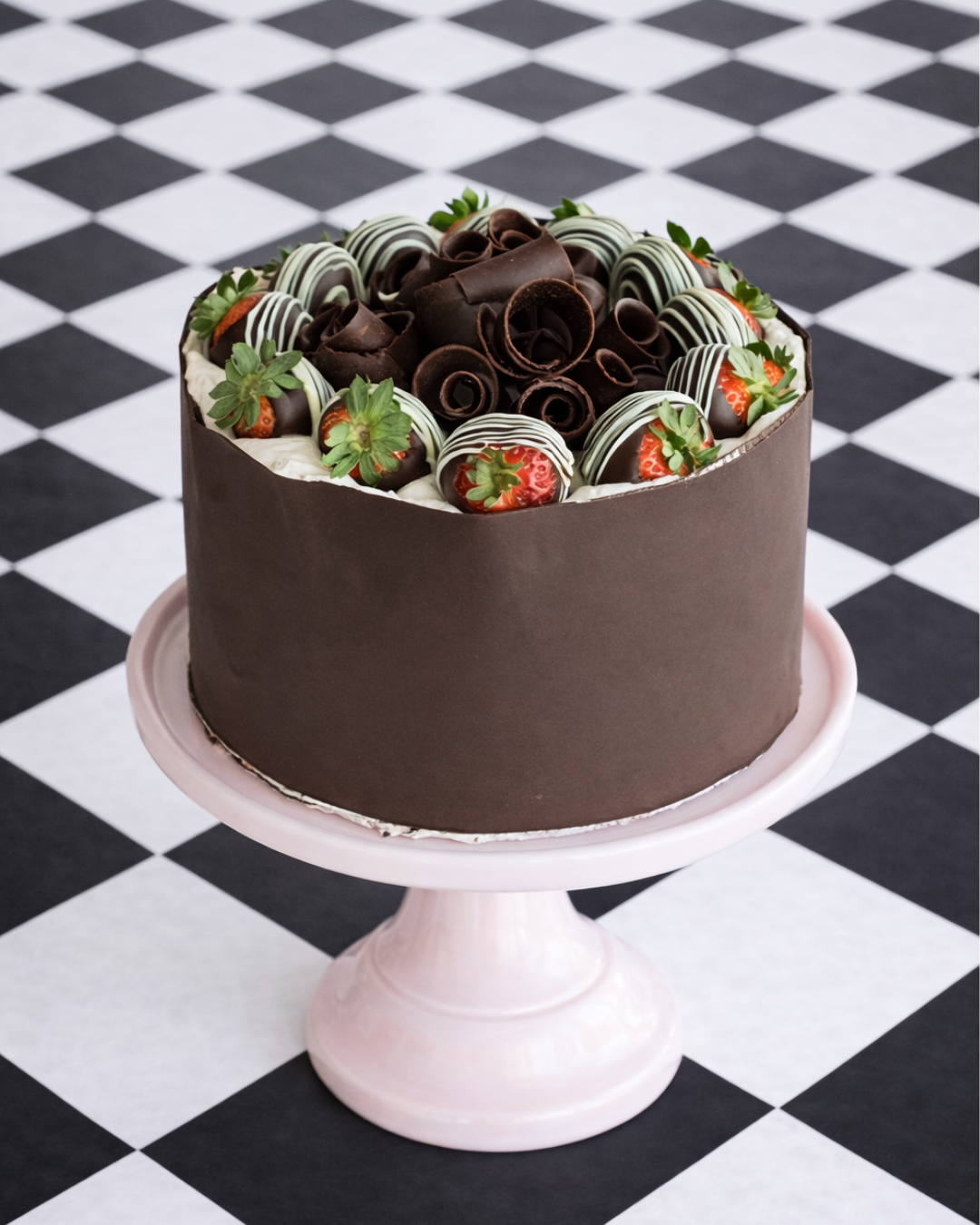 dark chocolate cake wrapped in chocolate with strawberries on top